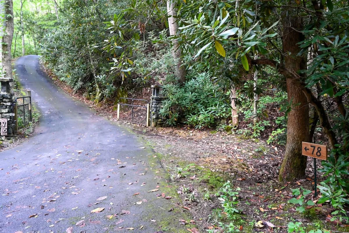 This image shows a serene winding road bordered by lush greenery, with a sign marked '78' hinting at a possible trail or entrance. The road feels secluded and invites exploration, suggesting the start of an outdoor adventure.
